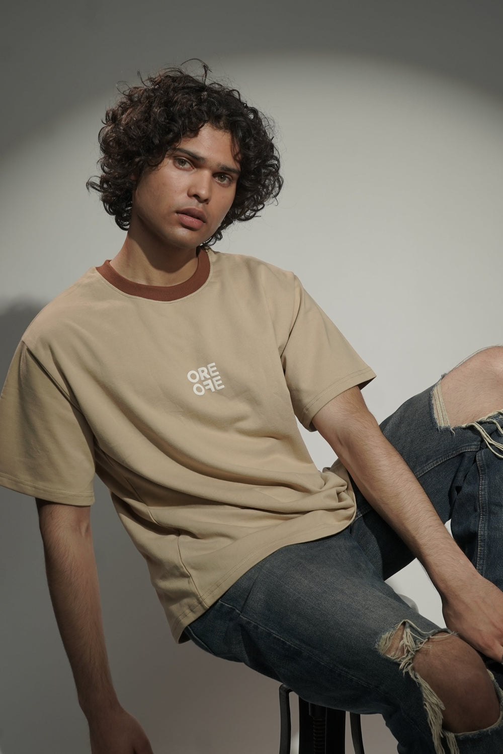 Model wearing Beige basic Oversized t-shirt and sitting on chair